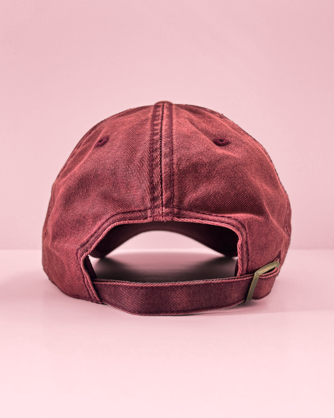 Read view of a maroon Filipina vintage cap resting on a flat pink surface.