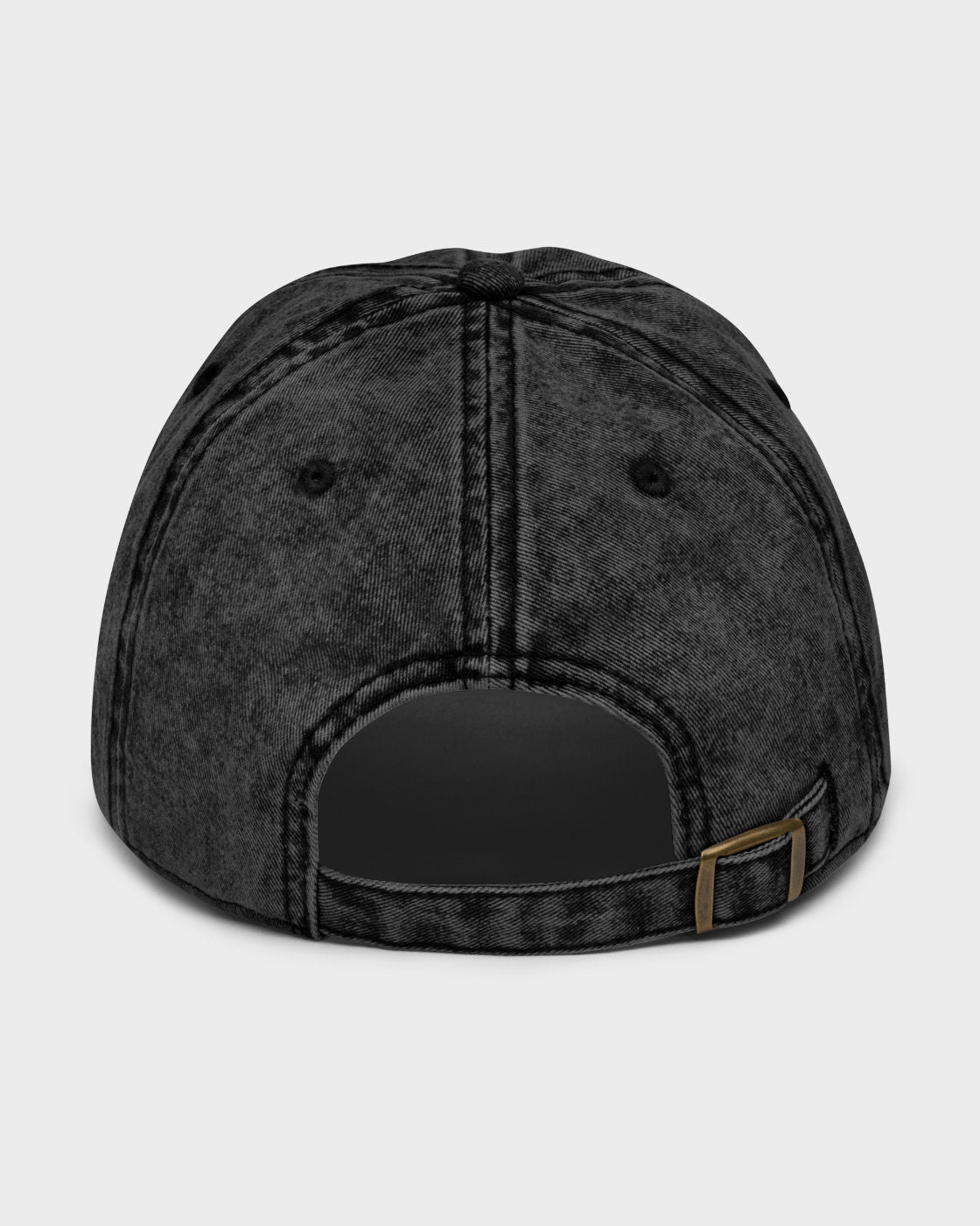 A washed black baseball cap shown from the back, featuring a curved snapback strap with a small gold-tone metal buckle, on a light gray background.