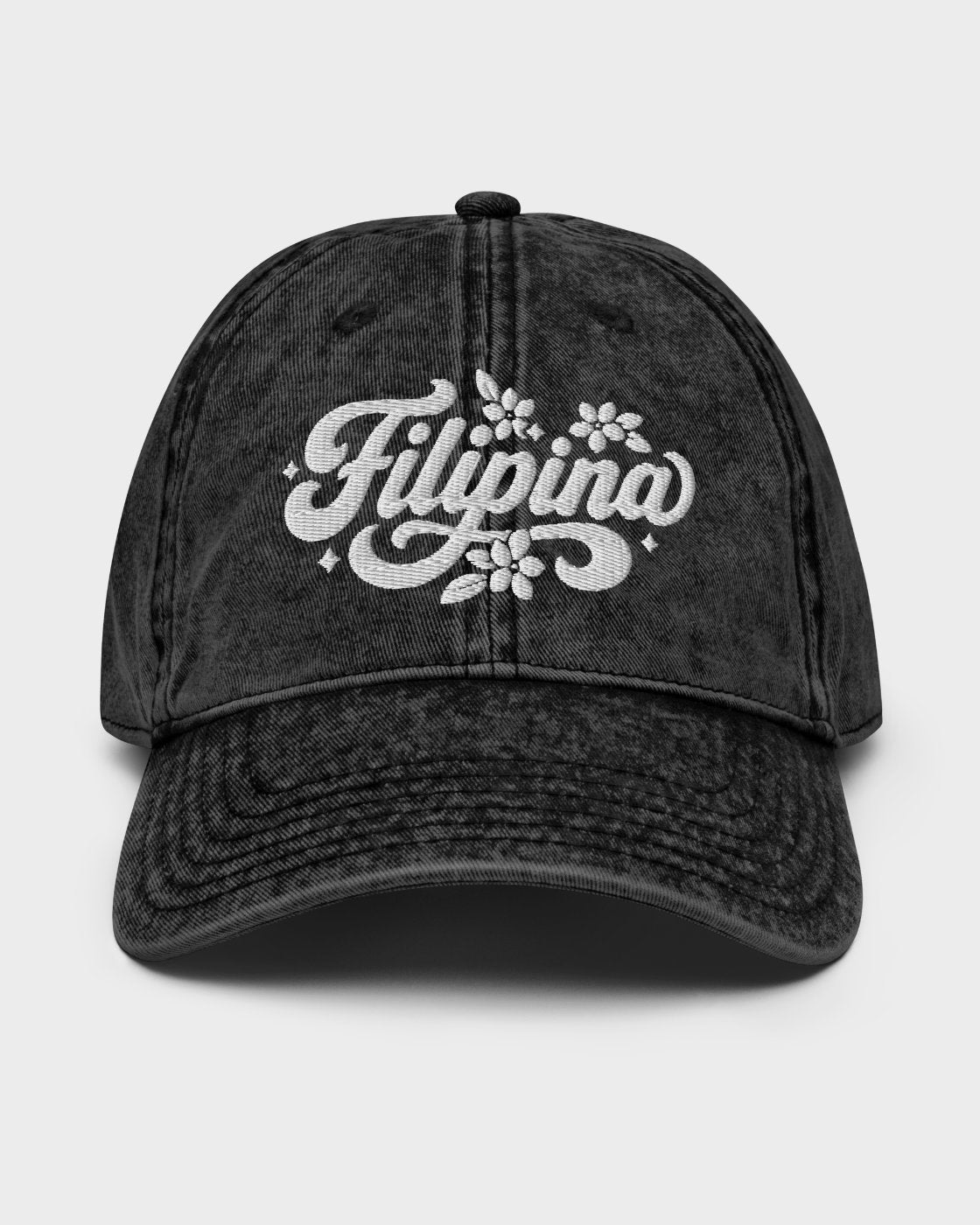 A black acid-wash baseball cap featuring a white embroidered 'Filipina' script with floral details on the front, set against a light gray background.