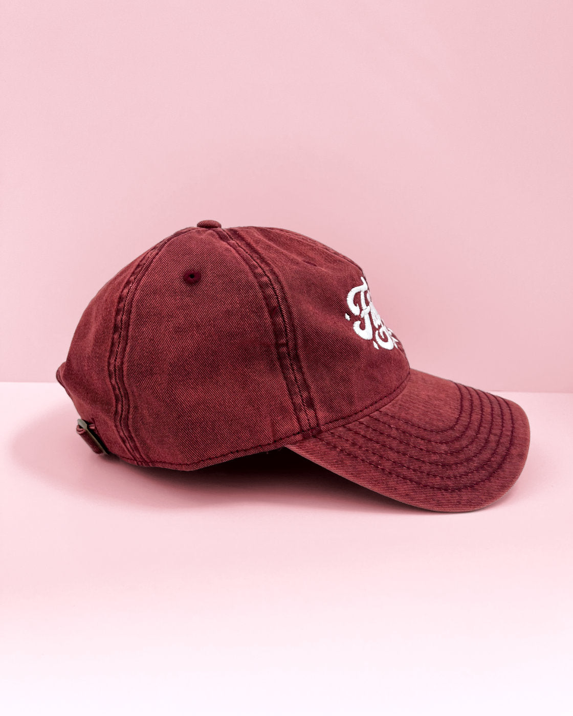 Side profile view of a maroon Filipina vintage cap resting on a flat pink surface.